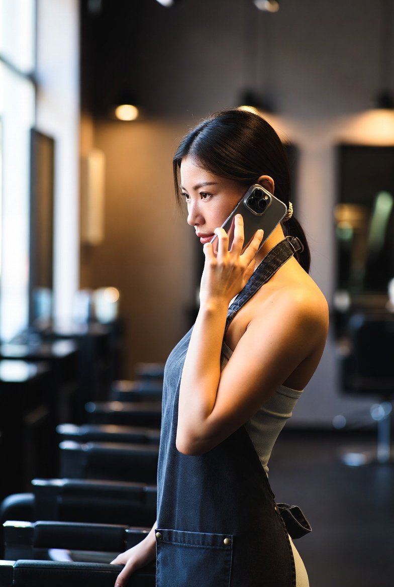 Texas cosmetologist on phone at salon station resolving a continuing education question