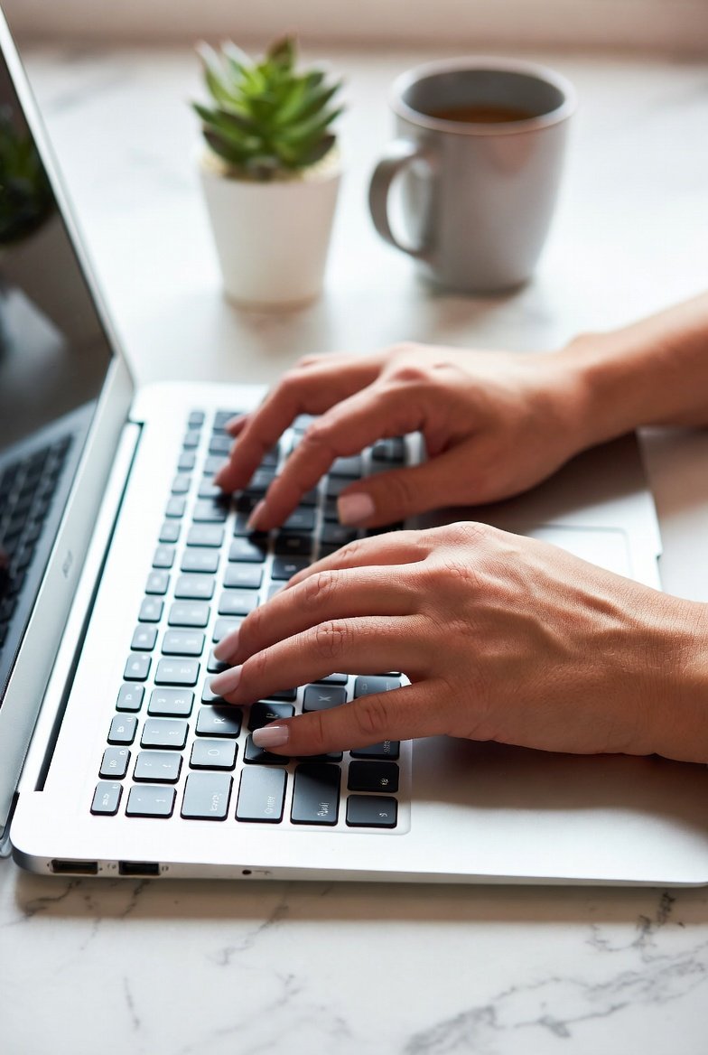 Close-up of cosmetologist's hands typing on laptop keyboard at modern salon station