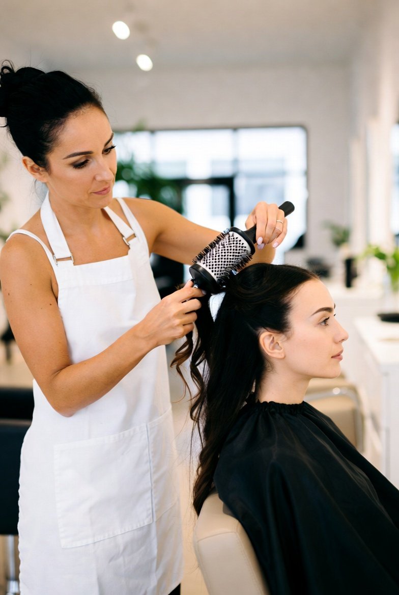 Cosmetologist practicing hairstyling technique on a client in a bright training salon