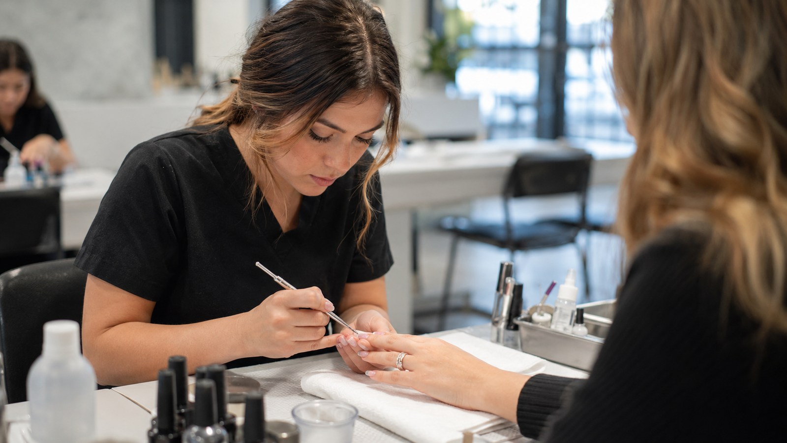 manicurist performing a nail service on a client